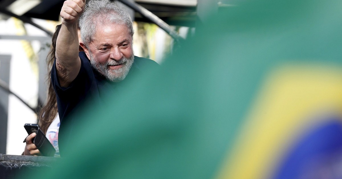 Former Brazil’s President Luiz Inacio Lula da Silva waves to supporters as he arrives at his apartment building after being detained for questioning in a federal investigation of a bribery and money laundering scheme in Sao Paulo