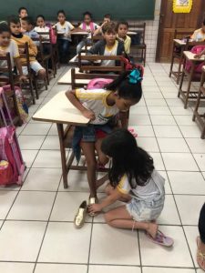revistapazes.com - Menina doa sapato e se ajoelha para calçar pés da coleguinha