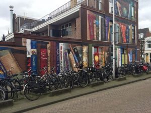 revistapazes.com - Artistas holandeses pintam estante gigante em um prédio de apartamentos com os livros favoritos dos moradores