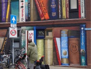 revistapazes.com - Artistas holandeses pintam estante gigante em um prédio de apartamentos com os livros favoritos dos moradores
