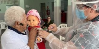 Senhora se vacina contra COVID-19 e pede para que sua filha boneca seja vacinada também