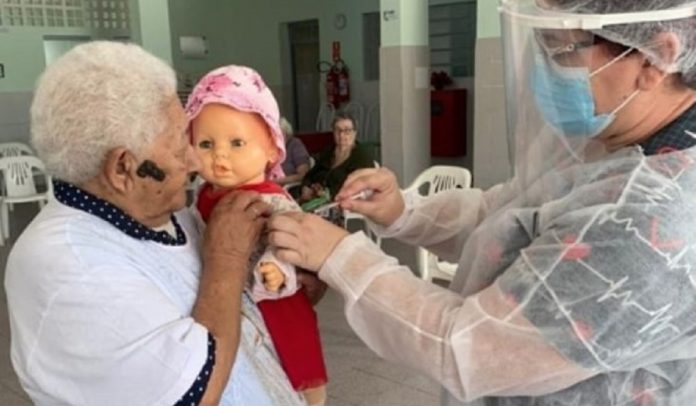 Senhora se vacina contra COVID-19 e pede para que sua filha boneca seja vacinada também