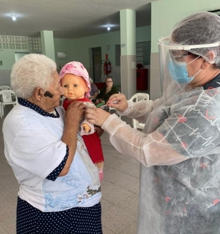 revistapazes.com - Senhora se vacina contra COVID-19 e pede para que sua filha boneca seja vacinada também